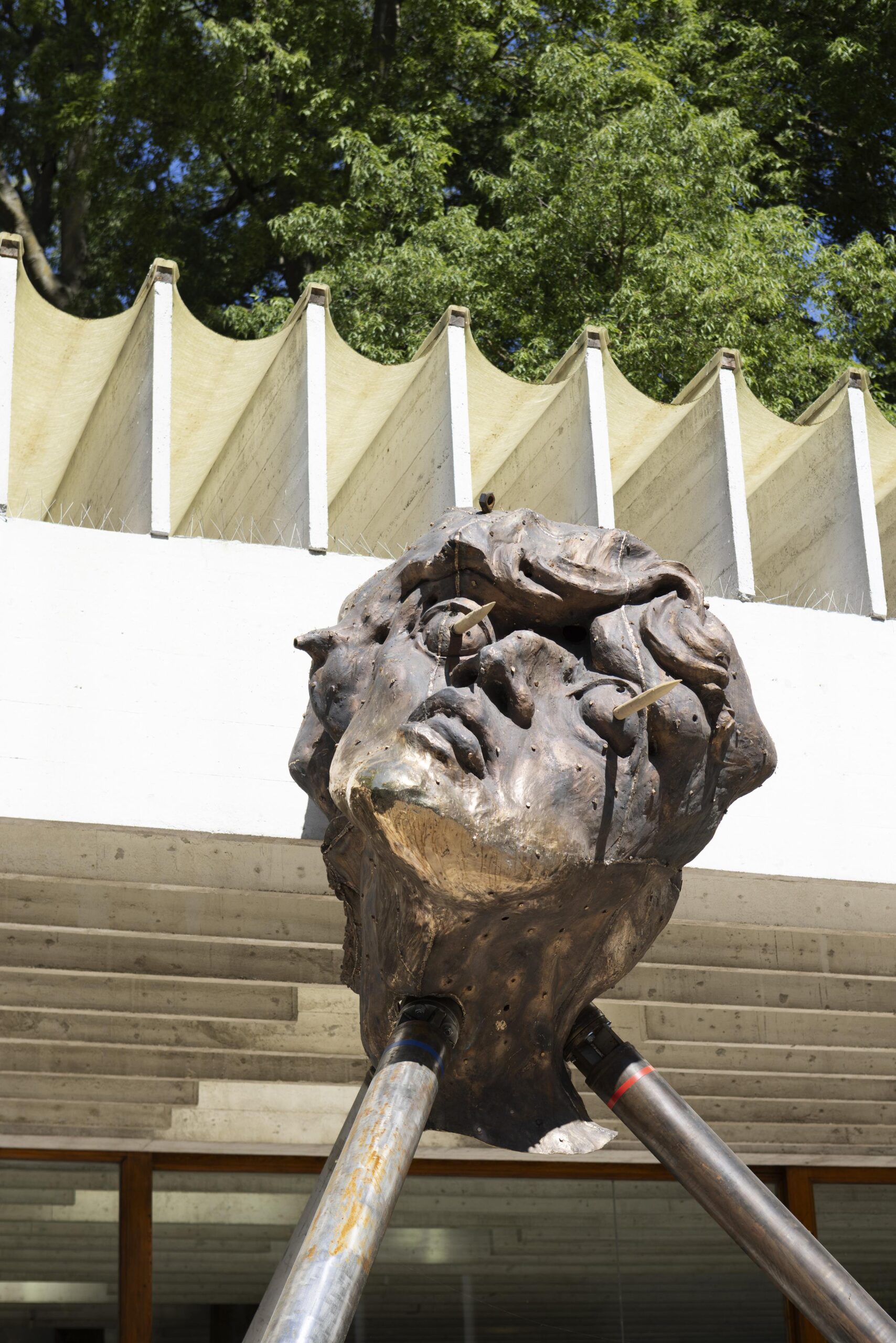 Benjamin Orlow, Ritual City, 2026 : tête sculptée portée par des pieux métalliques devant la façade du Pavillon nordique à Venise.