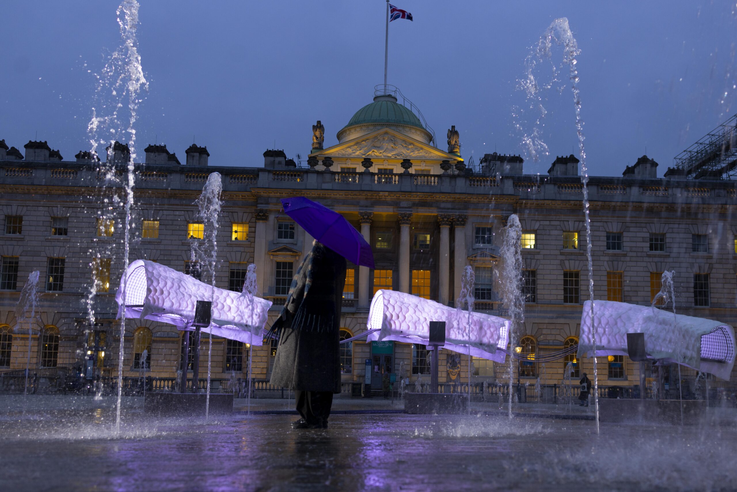 Serpentine Currents de Dana-Fiona Armour : fragments lumineux d’un serpent suspendus au-dessus des fontaines de Somerset House à la tombée du jour.