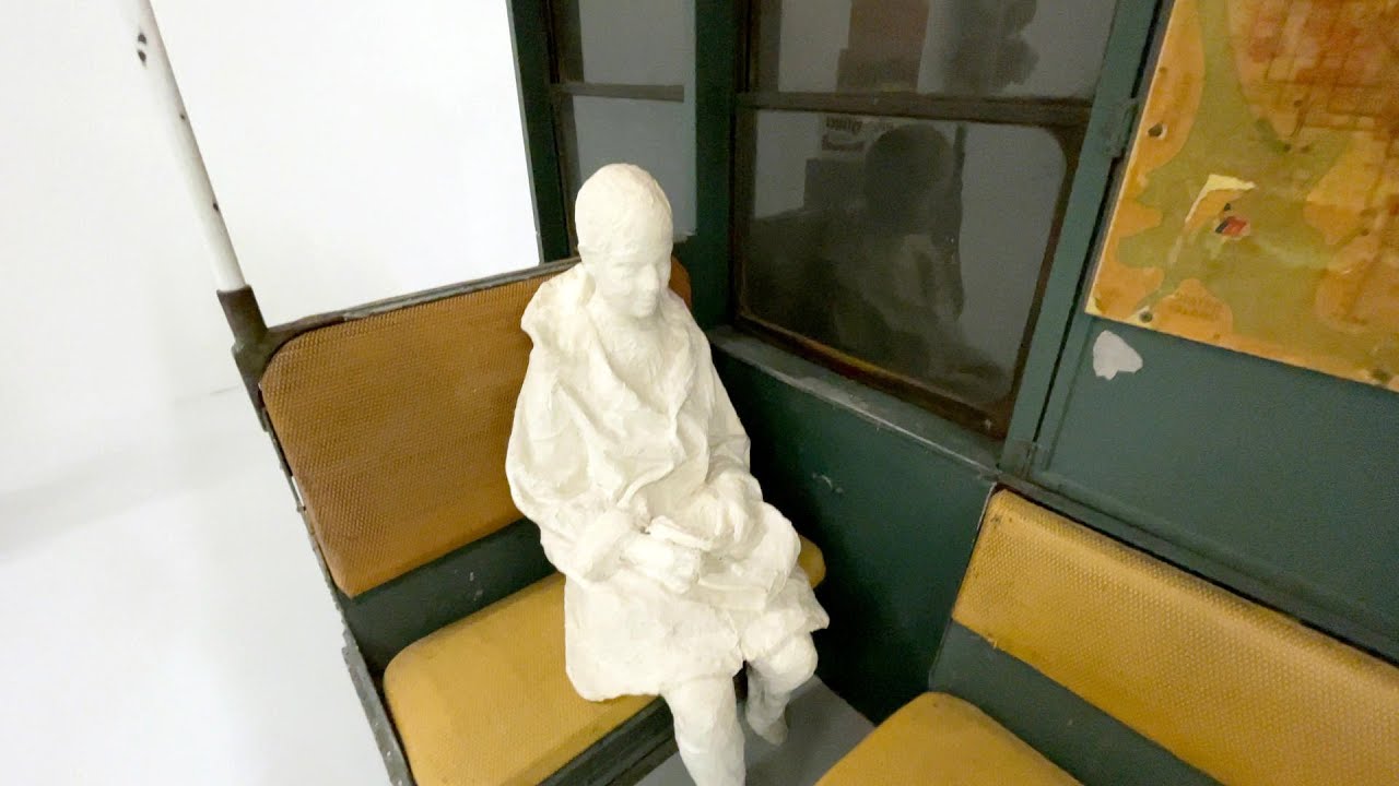 Figure en plâtre assise dans un fragment de voiture de métro.