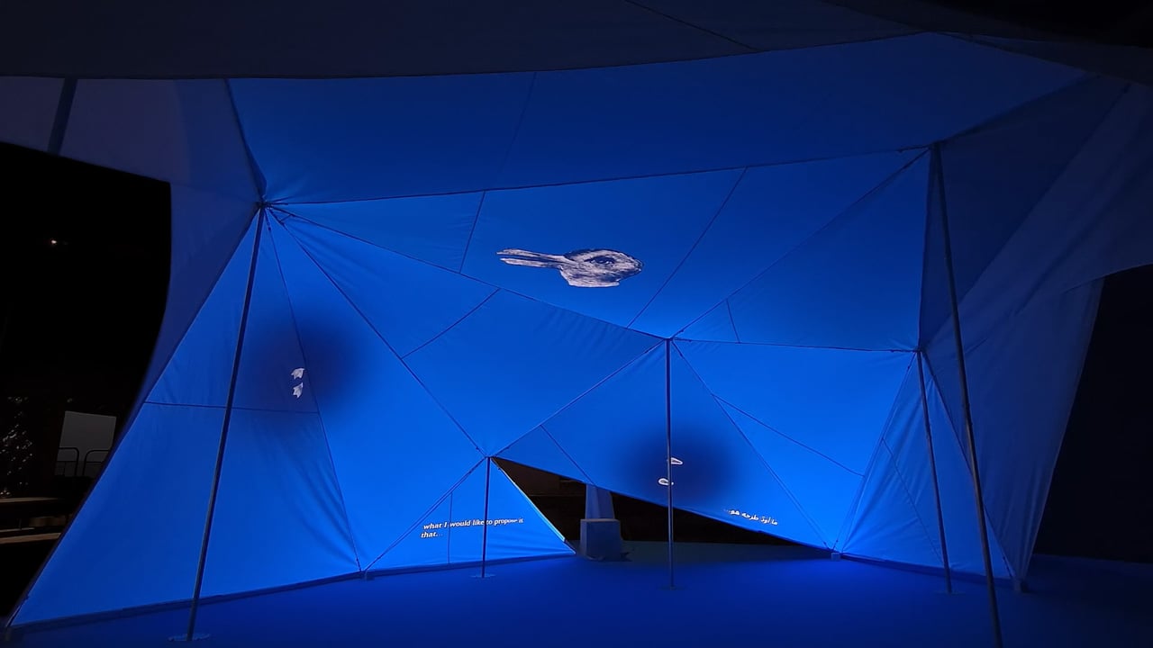 Projections bleues sur les surfaces de tissu anguleuses de l’installation Hold.