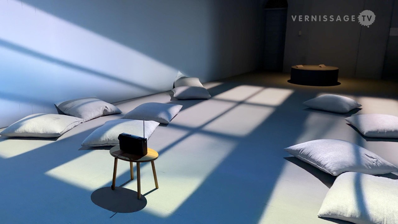 Coussins et chaise disposés dans un espace traversé par la lumière.