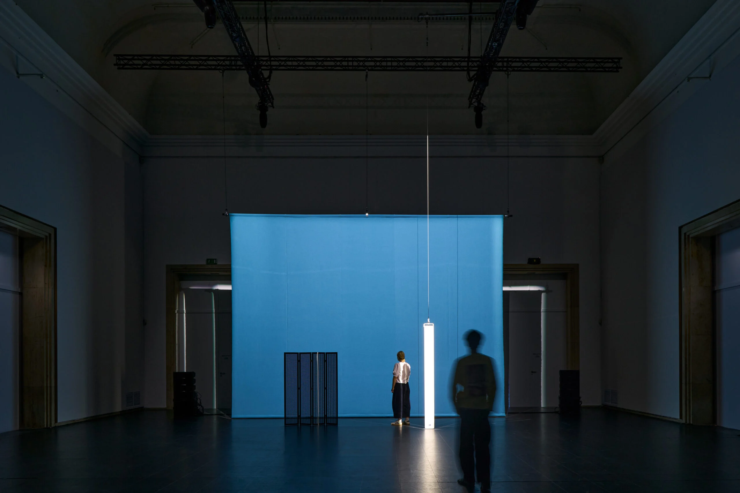 Installation FAVN de Florian Hecker à la Haus der Kunst : visiteurs, enceintes et lumière suspendue devant une surface bleue.