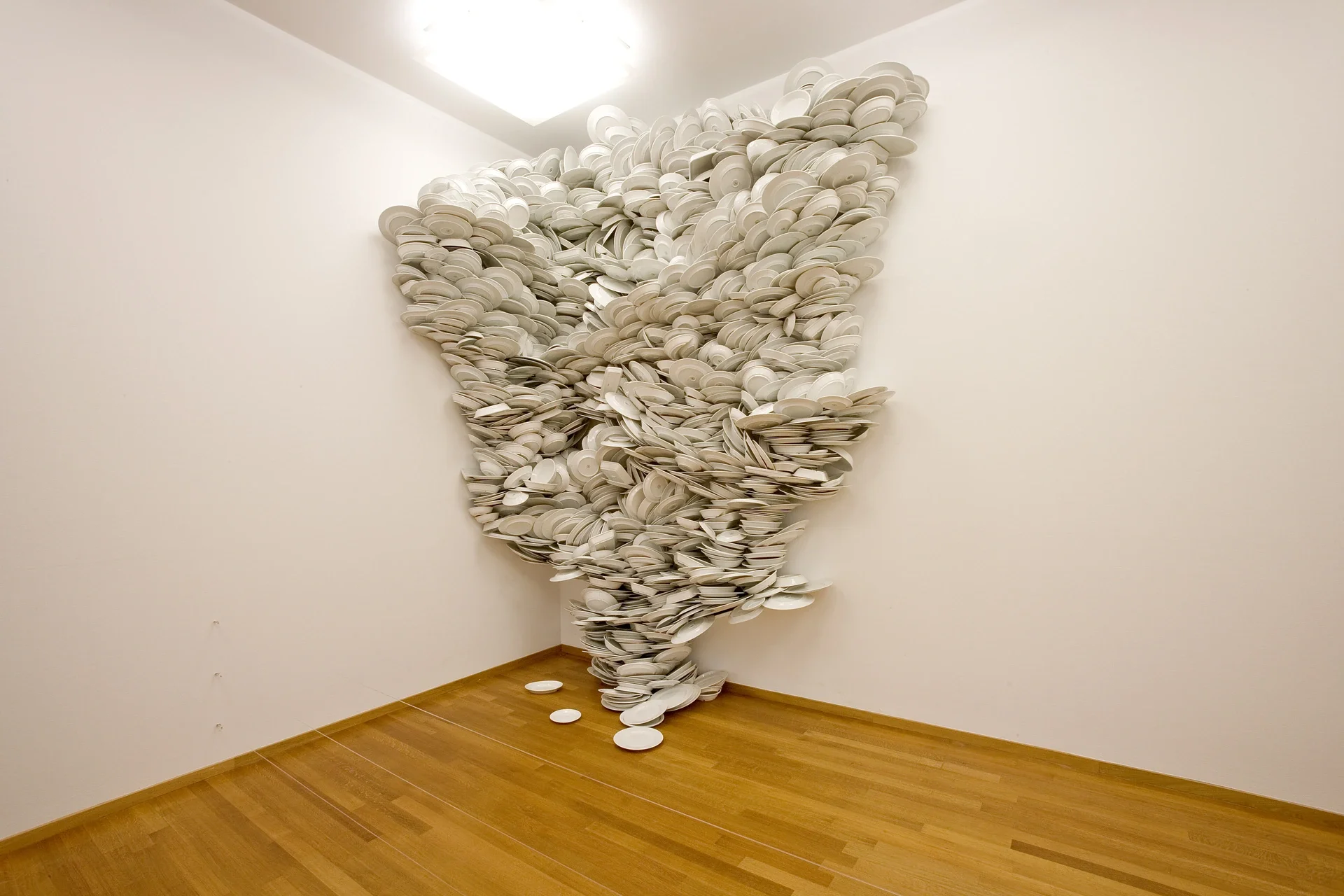 Hard Water de Zeger Reyers : une cascade de centaines d’assiettes de porcelaine blanche occupe l’angle d’une salle au Gemeentemuseum Den Haag.